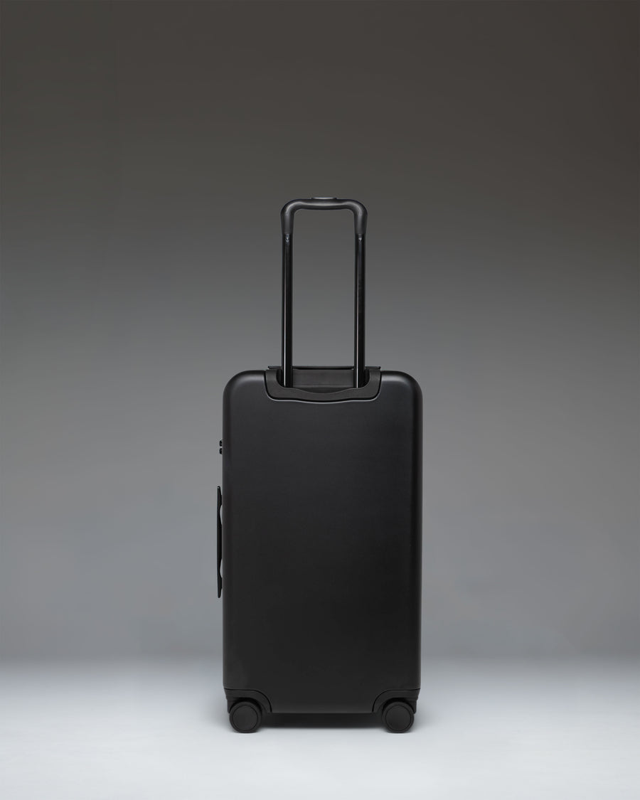 Black Herschel Heritage Hardshell Medium Luggage, featuring a durable textured exterior, robust wheels, and a telescopic handle.