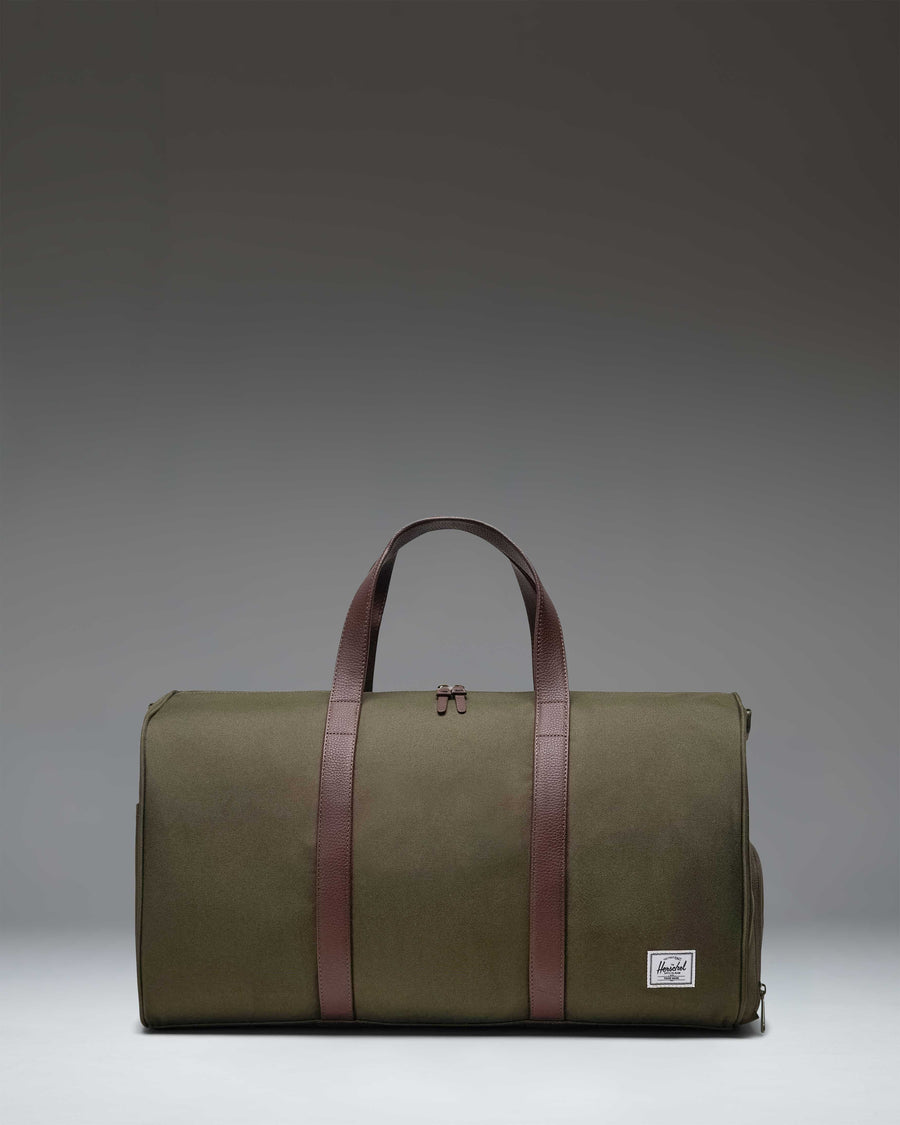 Herschel Novel Duffle bag in Ivy Green, featuring a classic duffle design with top handles, a shoulder strap, and a signature shoe compartment.