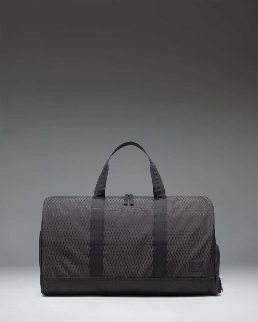 Herschel Novel Duffle bag in Black Diamond/Black color, showing a side view of the clean, textured fabric design with carry handles and shoulder strap.