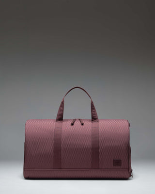 Herschel Novel Duffle bag in Huckleberry Diamond, a deep purple textured fabric with top handles, removable shoulder strap, and signature shoe compartment.