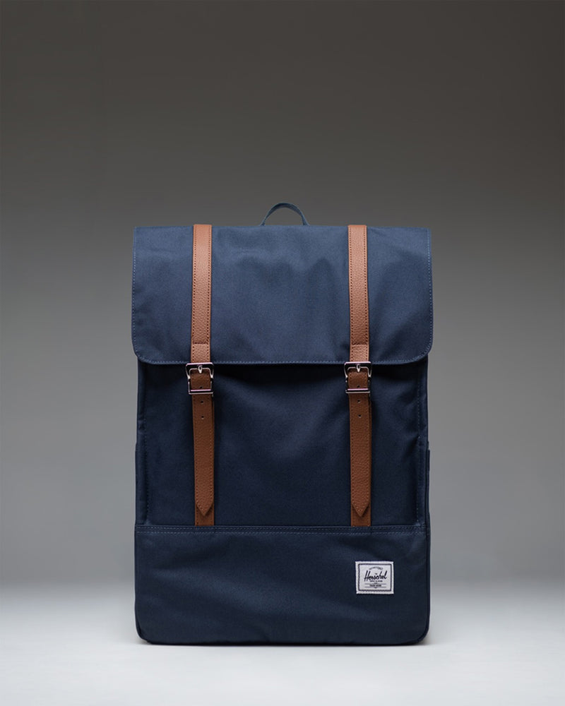 Herschel Survey Backpack in navy blue, showing the front view with its classic rectangular shape and dual strap closures.