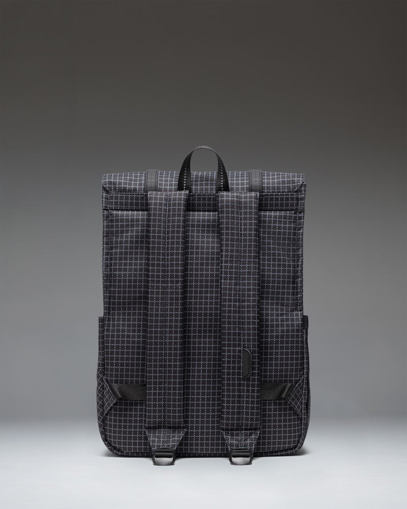 Herschel Survey Backpack in Grid - Black shown from the side, highlighting its slim profile, adjustable shoulder straps, and durable design.