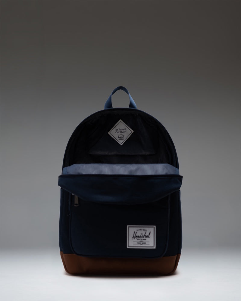 Herschel Supply Co. Pop Quiz Backpack in navy blue with a tan synthetic leather base and front pocket detailing.