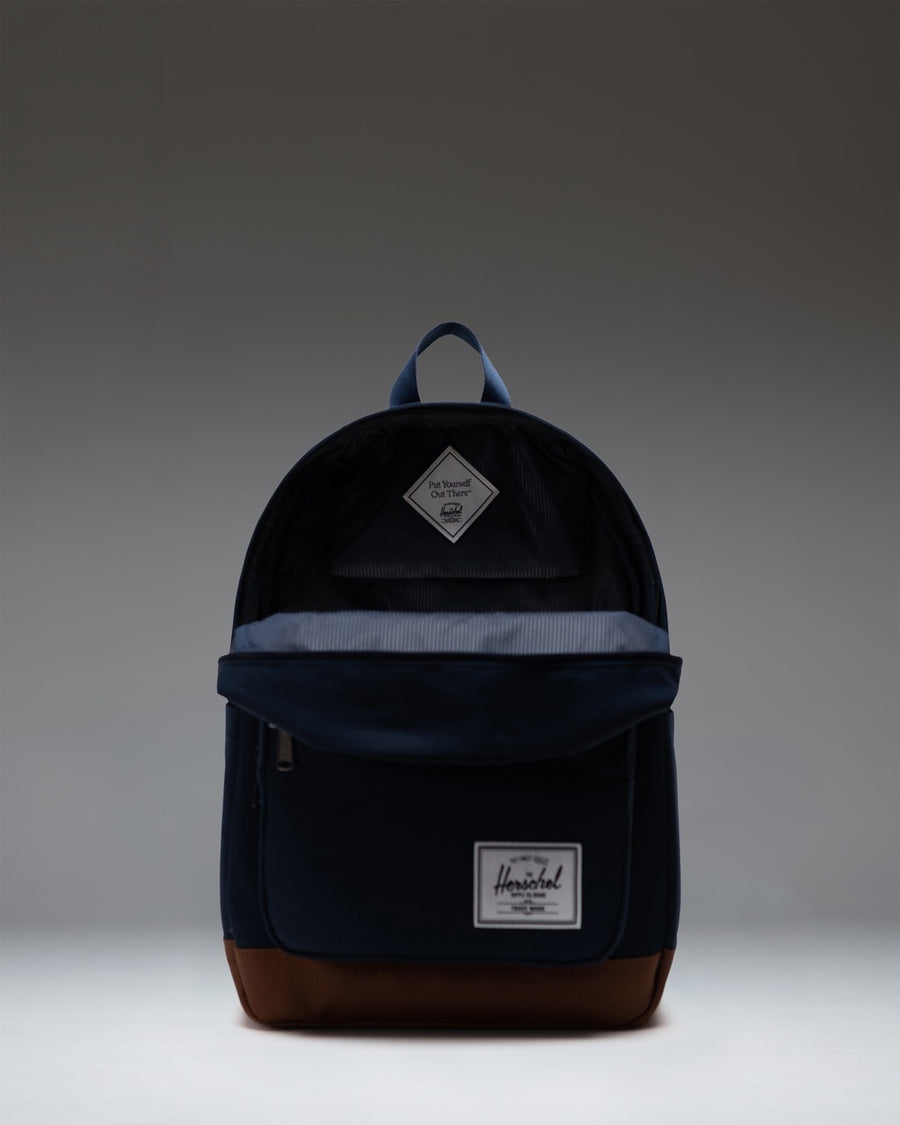Herschel Supply Co. Pop Quiz Backpack in navy blue with a tan synthetic leather base and front pocket detailing.