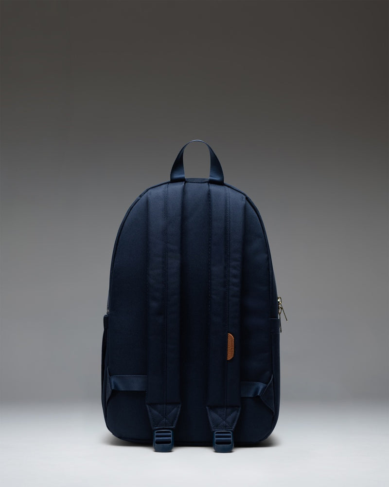 The Herschel Supply Co. Settlement Backpack in navy blue, featuring a classic design with a front storage pocket and exposed zippers.