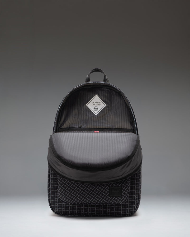 Herschel Supply Co. Settlement Backpack in Grid - Black, showing a close-up of the front zipper pocket and classic woven label.
