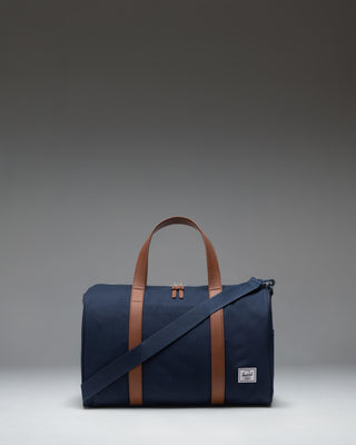 Herschel Novel Carry On Duffle in navy blue featuring a signature shoe compartment, top handles, and a removable shoulder strap.