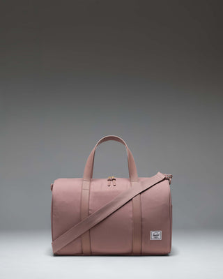 Herschel Supply Co. Novel Carry On Duffle bag in Ash Rose, a soft pink duffel with top handles and a removable shoulder strap.
