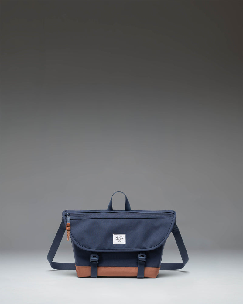 Herschel Supply Co Cove Small Messenger bag in Navy and Saddle Brown, showing a front view with the main flap and strap.