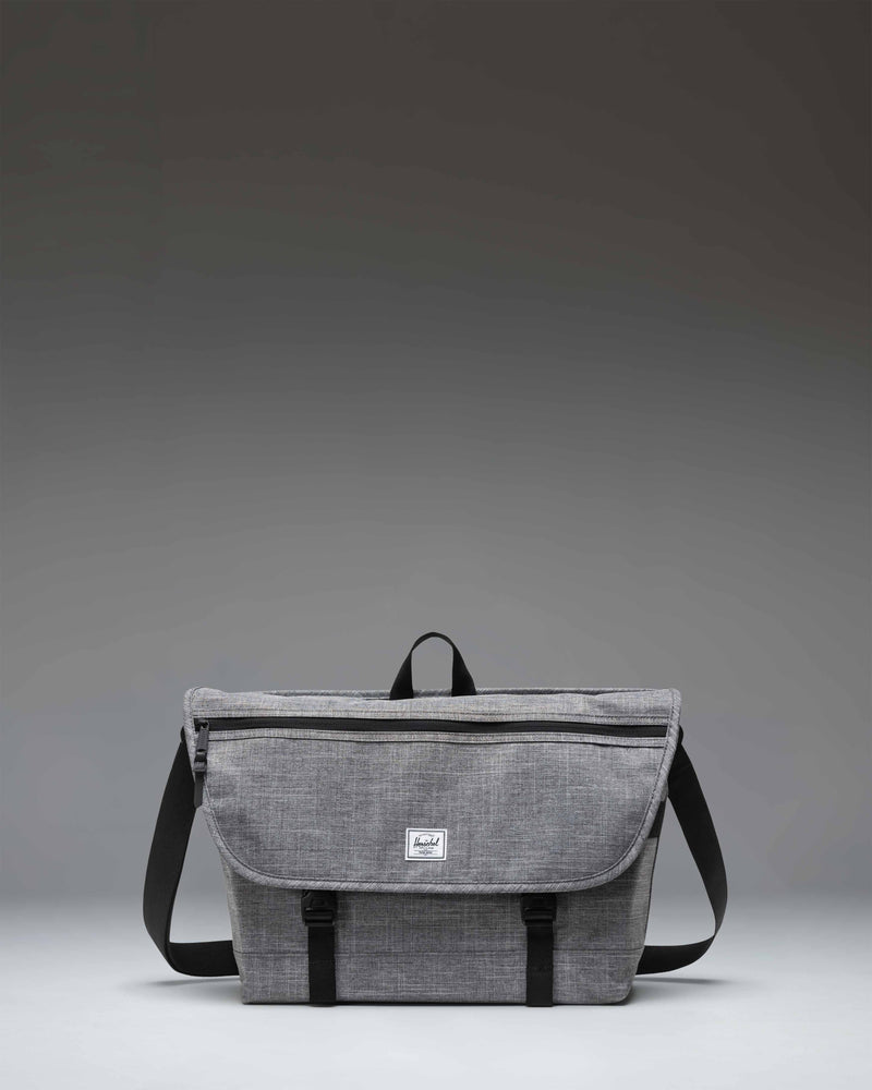 Herschel Supply Co. Cove Messenger bag in Raven Crosshatch grey, showing the front flap, buckle closure, and shoulder strap.