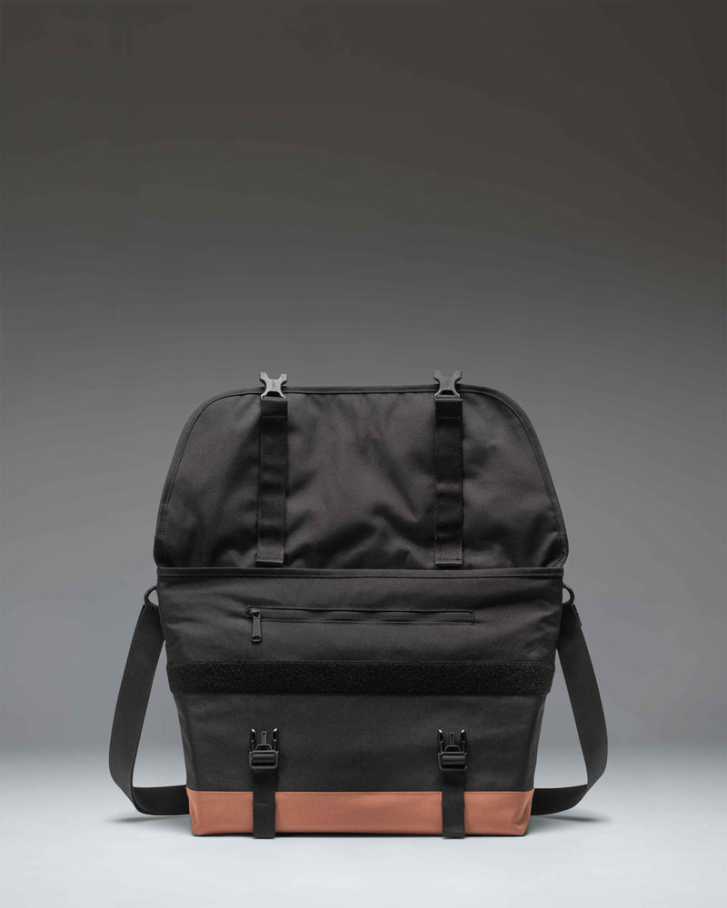 Herschel Supply Co. Cove Messenger bag in Black and Saddle Brown, showing a close-up lifestyle view of the crossbody strap and design.