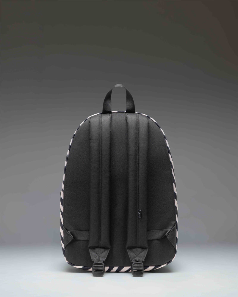 Herschel Supply Co. Classic Backpack in zebra print featuring black and white stripes with a front zippered pocket and a black branded patch.