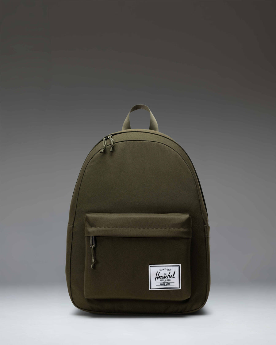 Herschel Classic Backpack in Ivy Green, showing a clean, minimalist design with a front storage pocket and classic woven label.