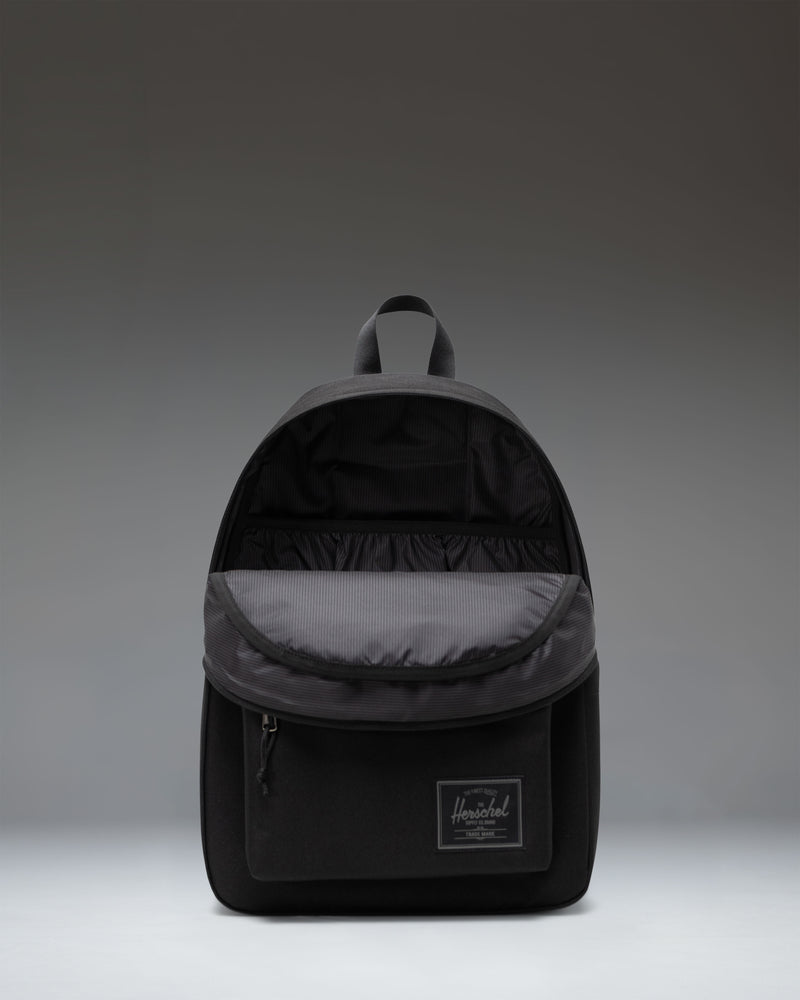 Herschel Classic Backpack in Black Tonal showcasing its clean, minimalist design with a front storage pocket and durable zippers.