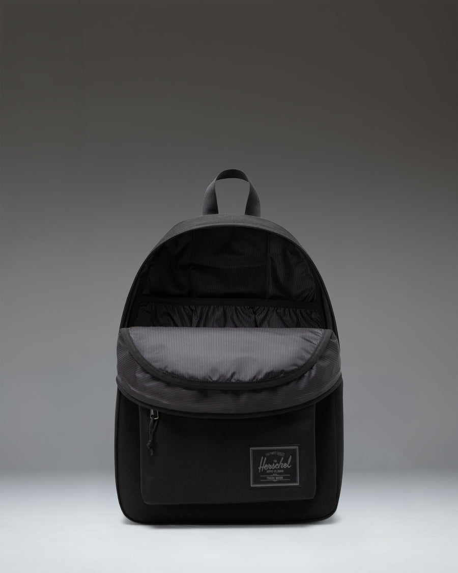 Herschel Classic Backpack in Black Tonal showcasing its clean, minimalist design with a front storage pocket and durable zippers.