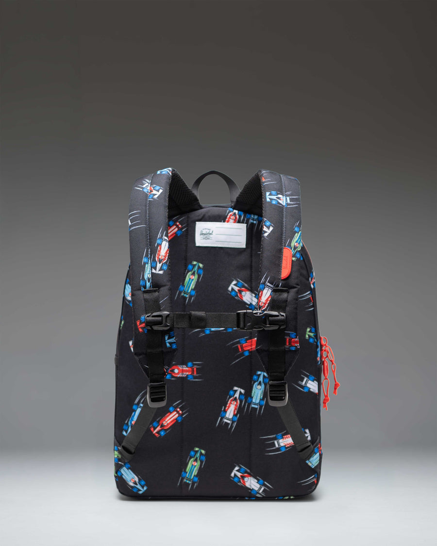 Herschel Heritage Youth Backpack in the Race Cars pattern featuring colorful race car graphics over a dark background.