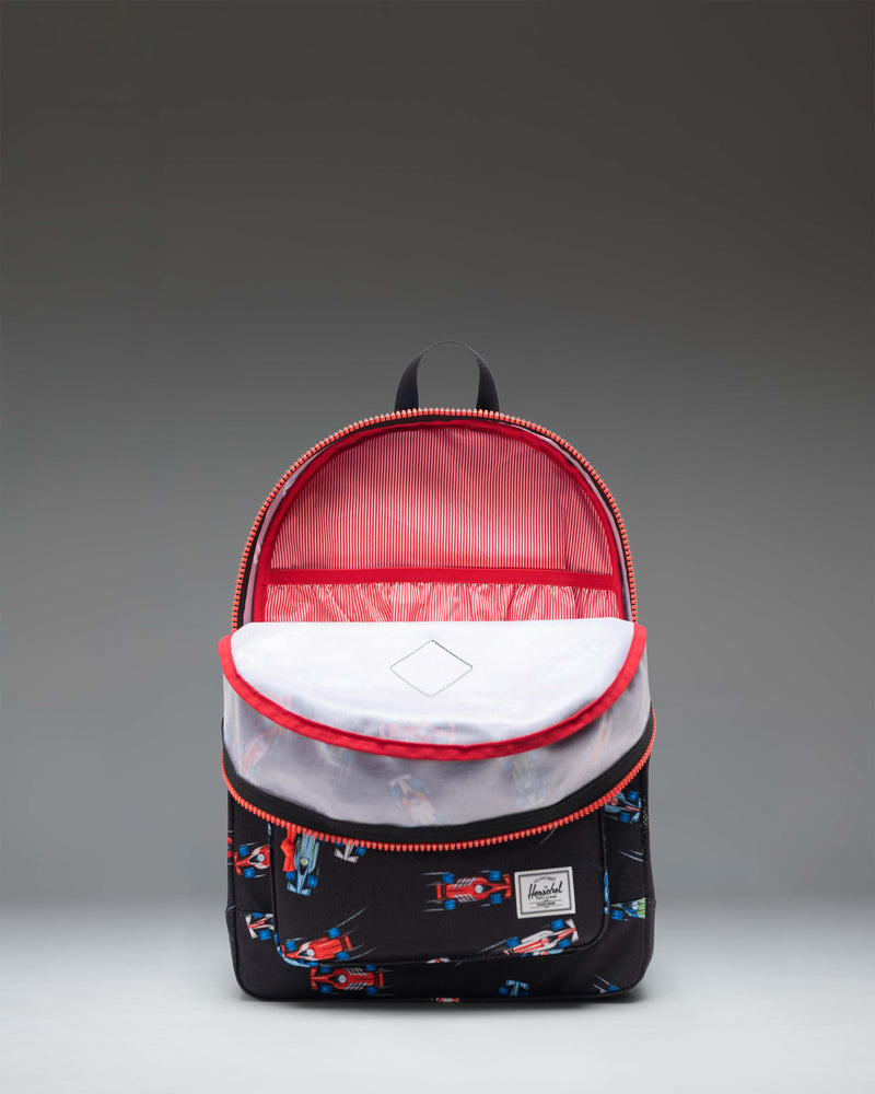 Herschel Heritage Youth Backpack in Race Cars color pattern featuring a black base with colorful car graphics, a front pocket, and a mesh side pocket.