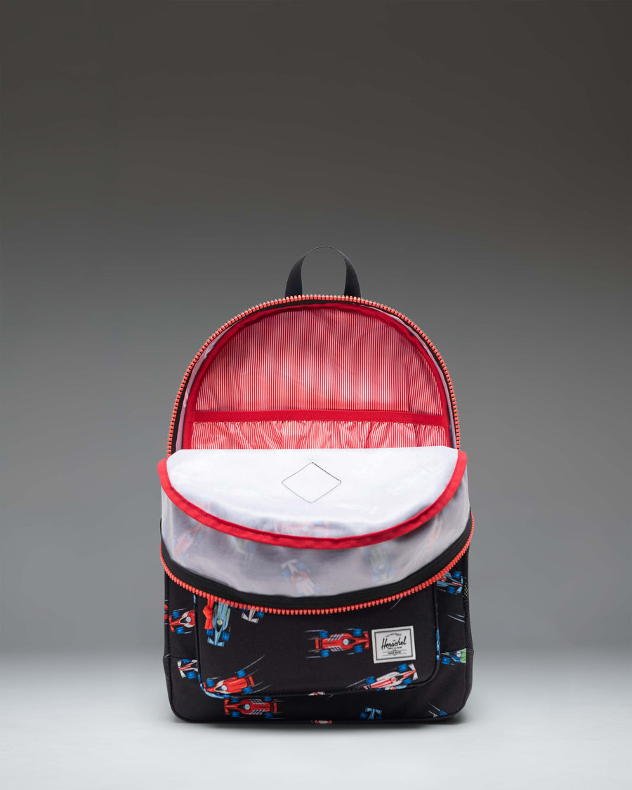 Herschel Heritage Youth Backpack in Race Cars color pattern featuring a black base with colorful car graphics, a front pocket, and a mesh side pocket.