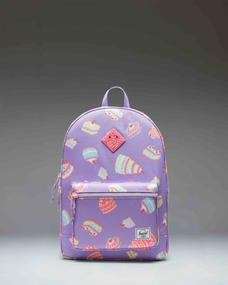 Herschel Heritage Youth Backpack in the Cakes colorway, featuring a playful print pattern with a front pocket and classic woven label.