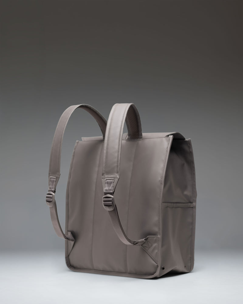 Herschel Supply Co. City Backpack in Dark Gull Gray shown from a side view, highlighting its slim profile and adjustable rubber strap closure.