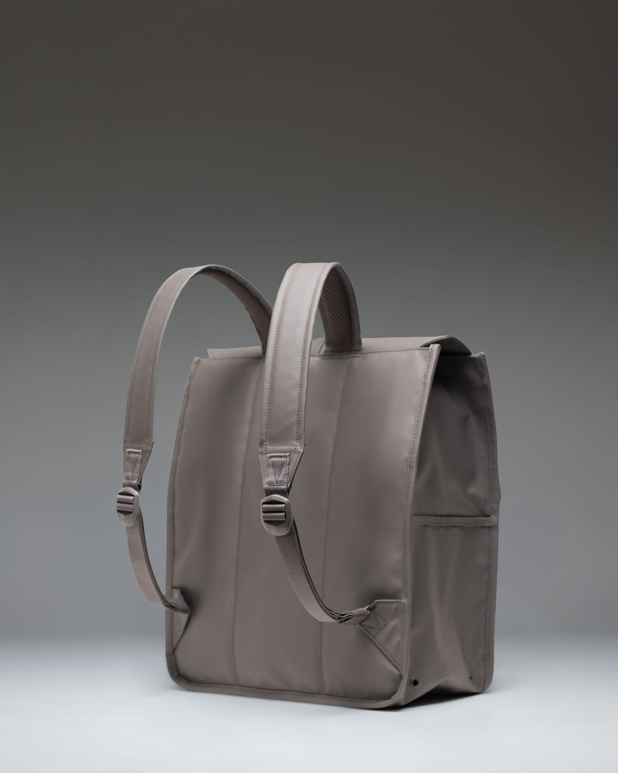 Herschel Supply Co. City Backpack in Dark Gull Gray shown from a side view, highlighting its slim profile and adjustable rubber strap closure.