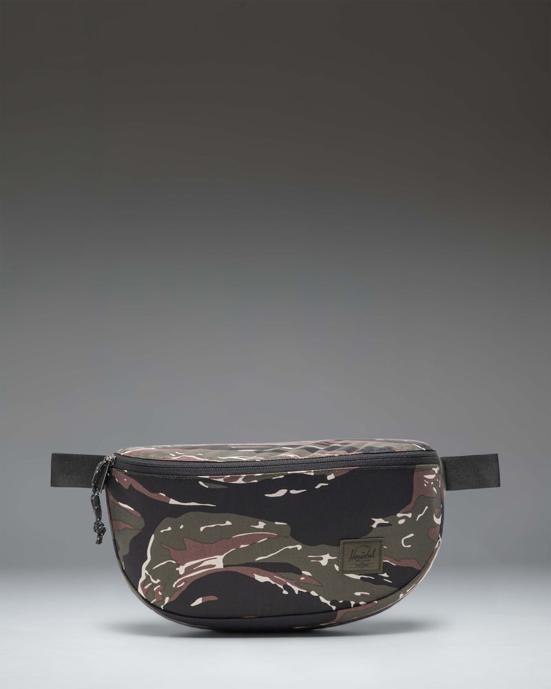 Herschel Supply Co. Kaine Hip Pack in Tiger Camo, showing the front view with zipper details and adjustable strap.