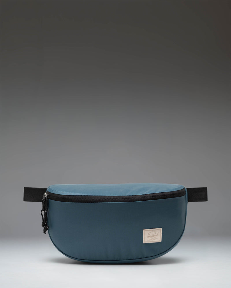 Herschel Supply Co. Kaine Hip Pack in Mediterranea blue, showing a slouchy silhouette with an adjustable strap and zippered closure.