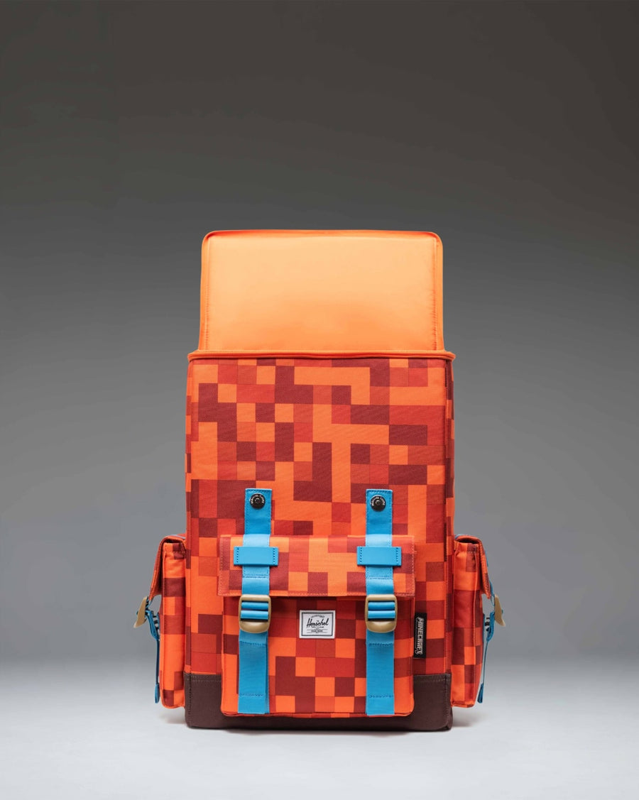 Minecraft Herschel Little America Cube Backpack in Orange Block pattern featuring pixelated dirt and grass graphics with dual orange straps.