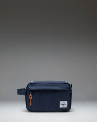 Herschel Supply Co. Chapter Travel Kit in navy blue, showing a side view of the structured travel pouch with a carrying handle.