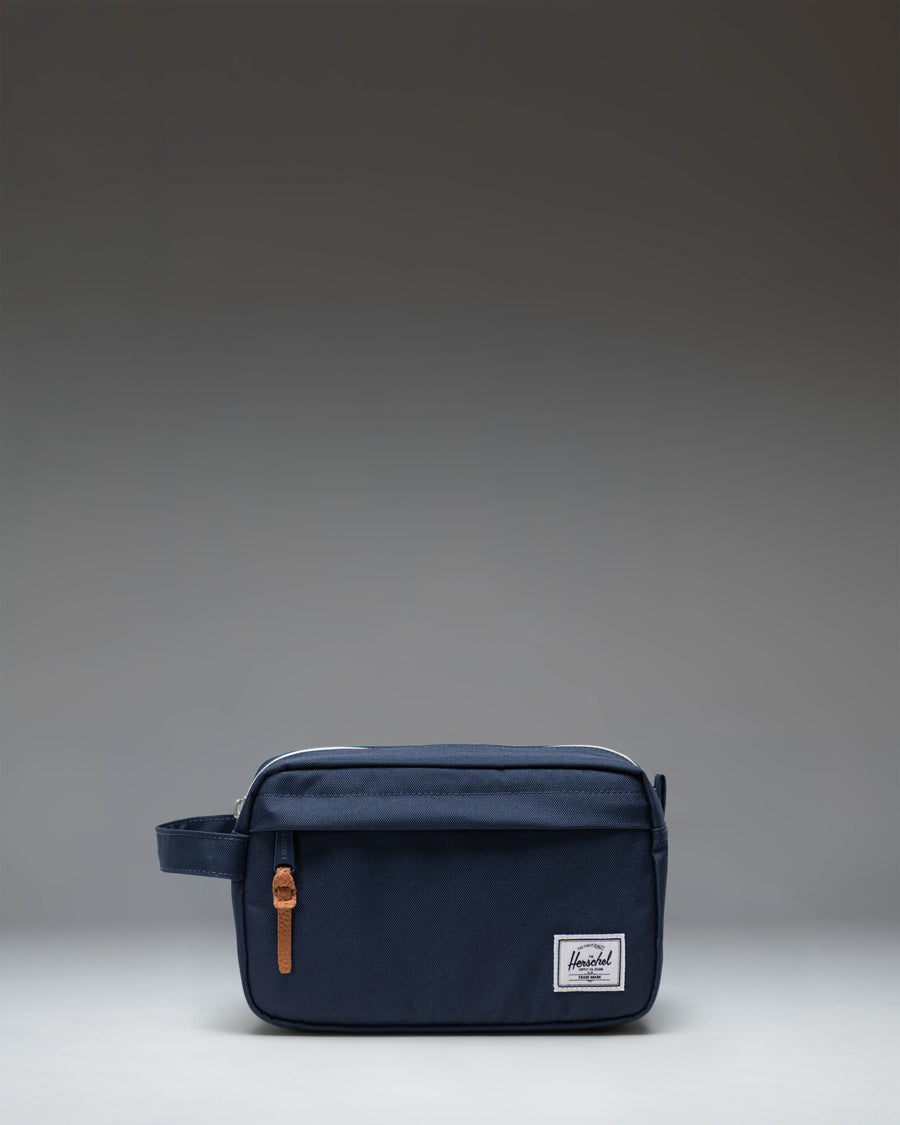 Herschel Supply Co. Chapter Travel Kit in navy blue, showing a side view of the structured travel pouch with a carrying handle.