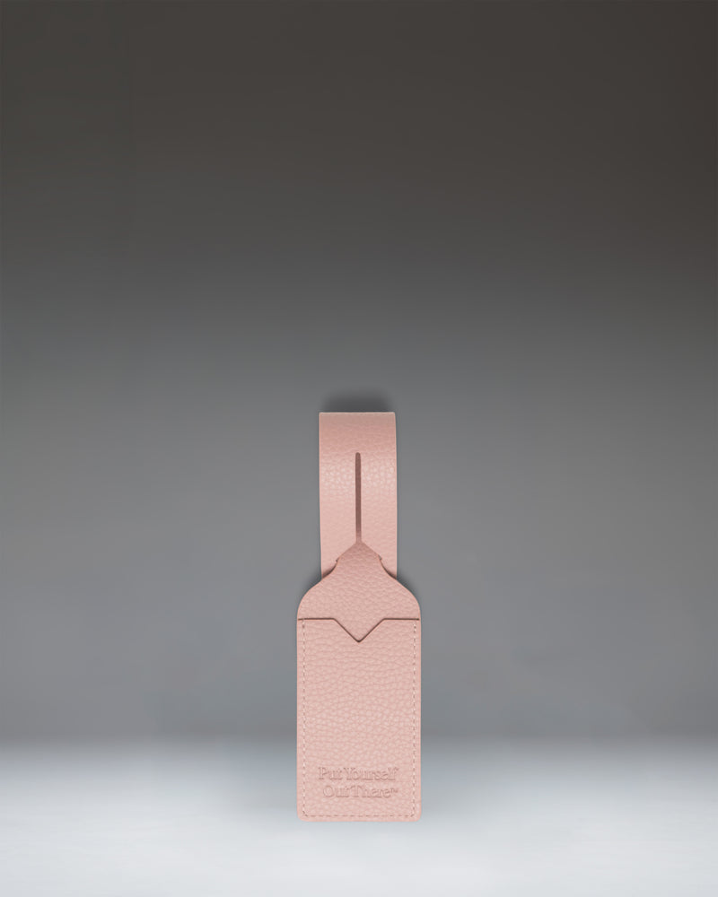 Herschel Supply Co. Ash Rose vegan leather luggage tag featuring an adjustable strap with a gold-tone buckle and a clear window for identification.