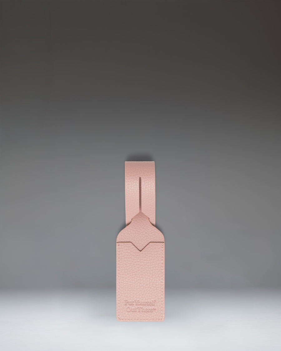 Herschel Supply Co. Ash Rose vegan leather luggage tag featuring an adjustable strap with a gold-tone buckle and a clear window for identification.