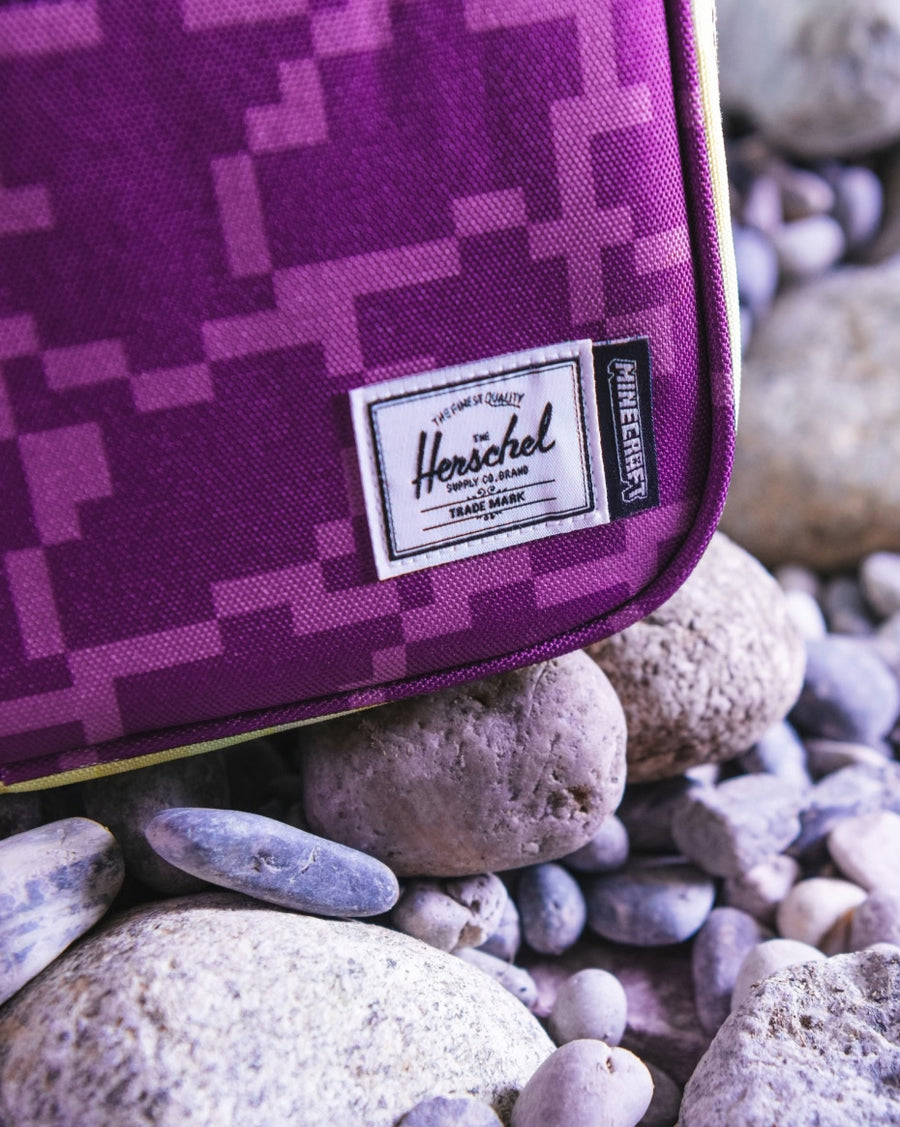 Herschel Supply Co. Minecraft Pop Quiz Lunch Box in The End pattern, featuring pixelated purple and black graphics.