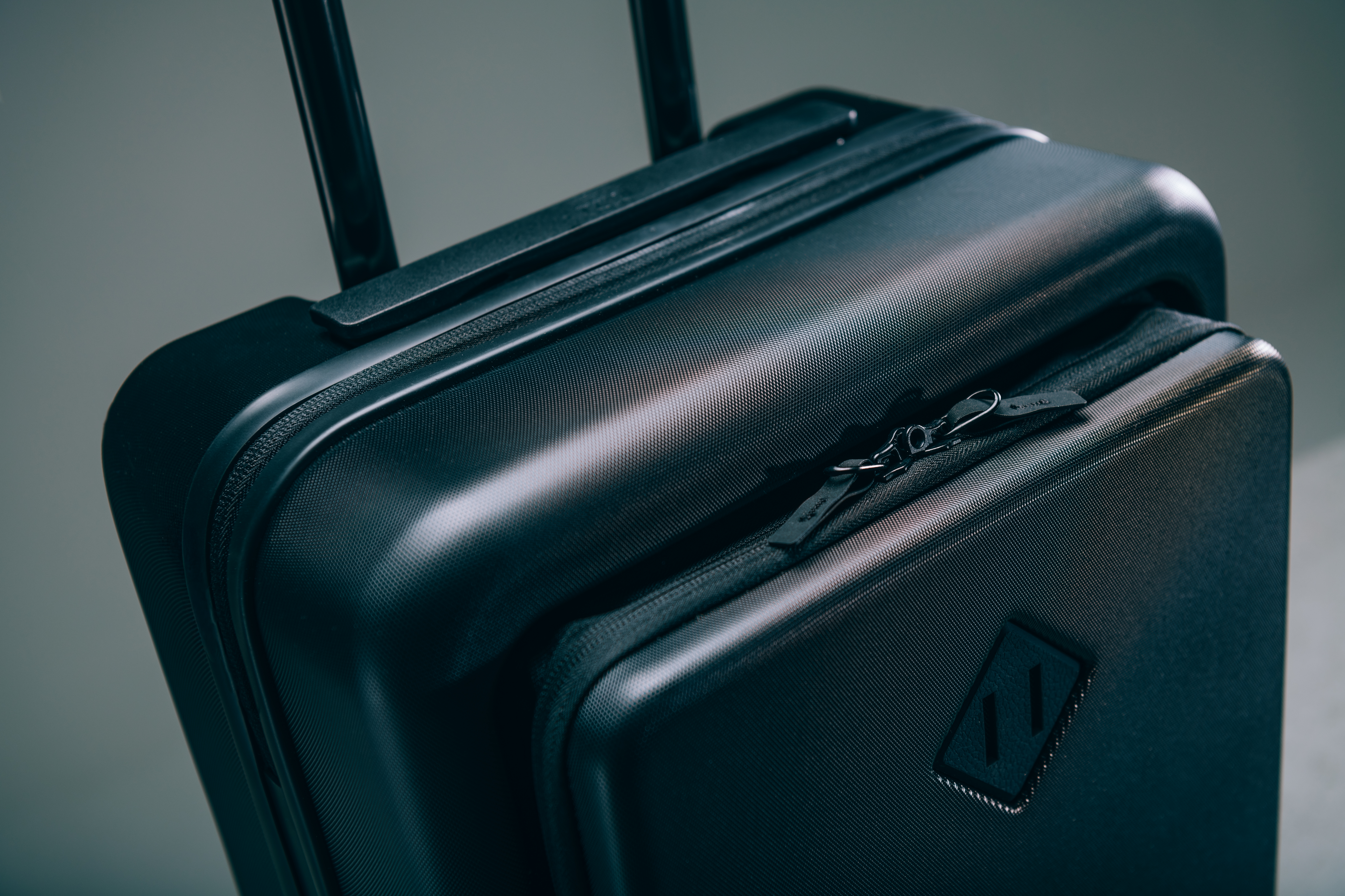 Black Herschel Heritage Hardshell Pro Large Carry On luggage with its front tech pocket open, showing a laptop and organized travel essentials.
