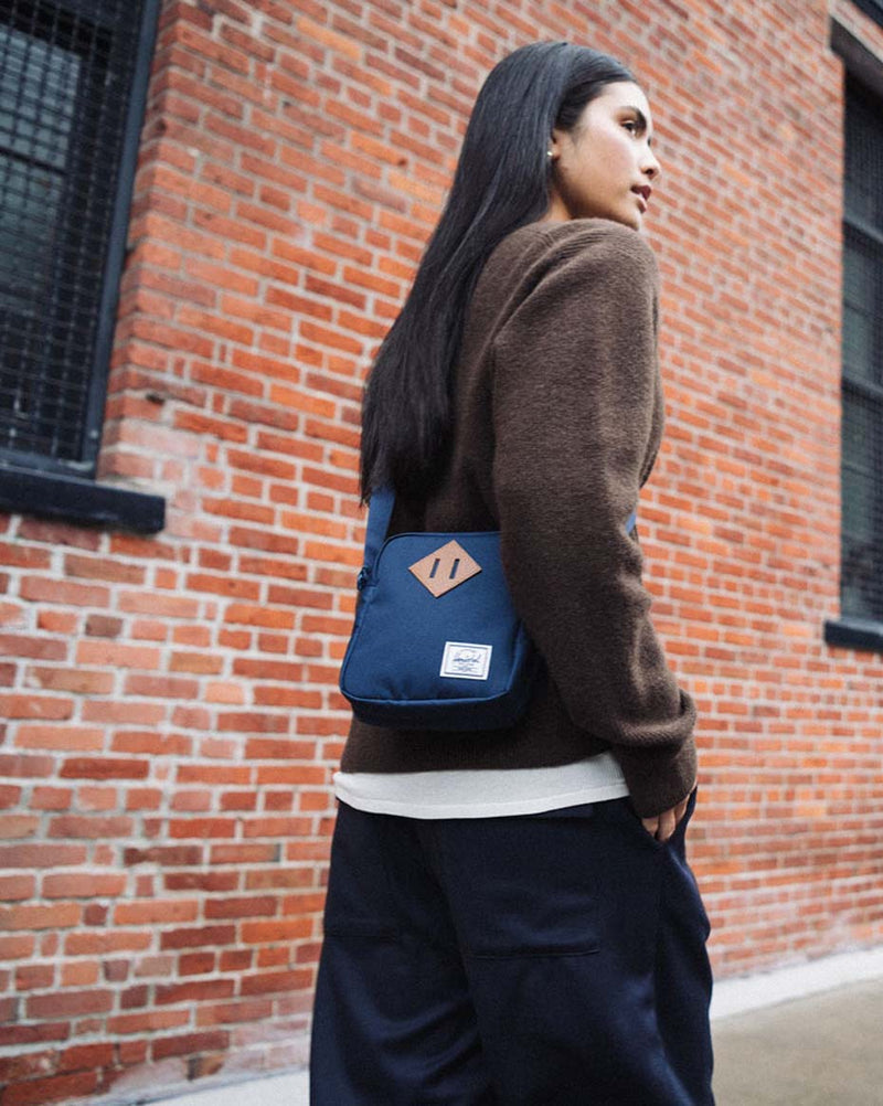 Herschel Heritage Crossbody bag in navy blue featuring a boxy style with a signature diamond detail and an adjustable shoulder strap.