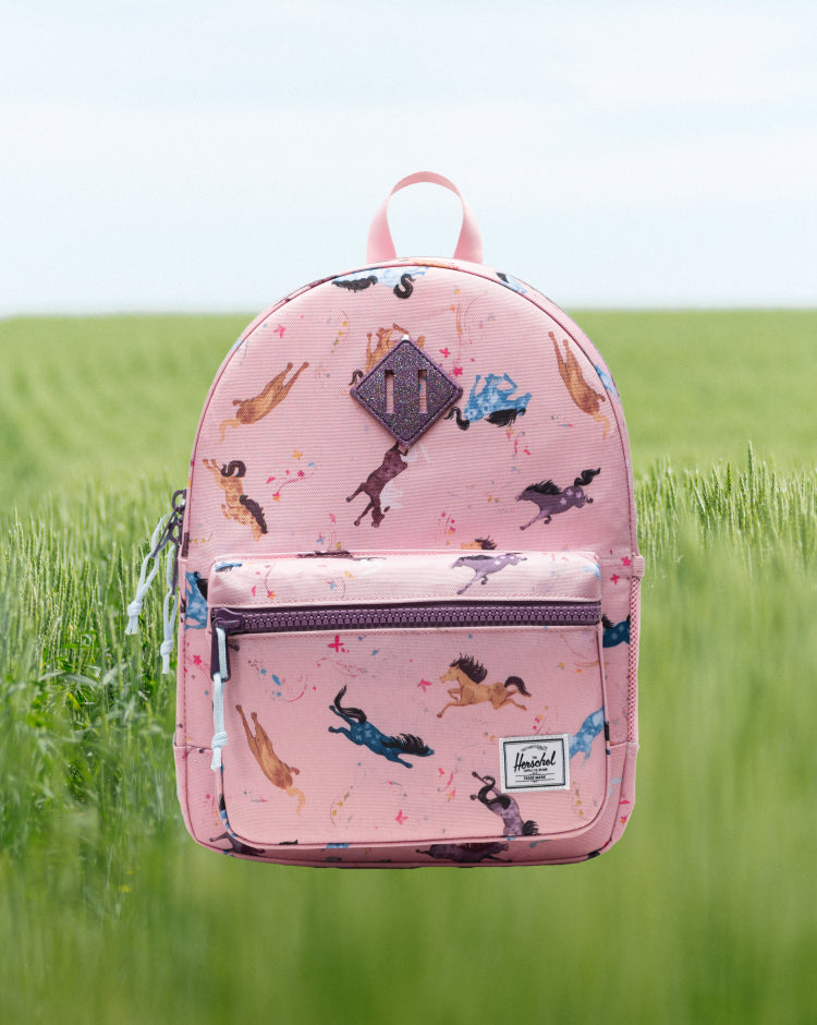 Herschel Heritage Kids Backpack in Wild Horses print, featuring a brown and tan horse pattern on a black background with a brown diamond accent.