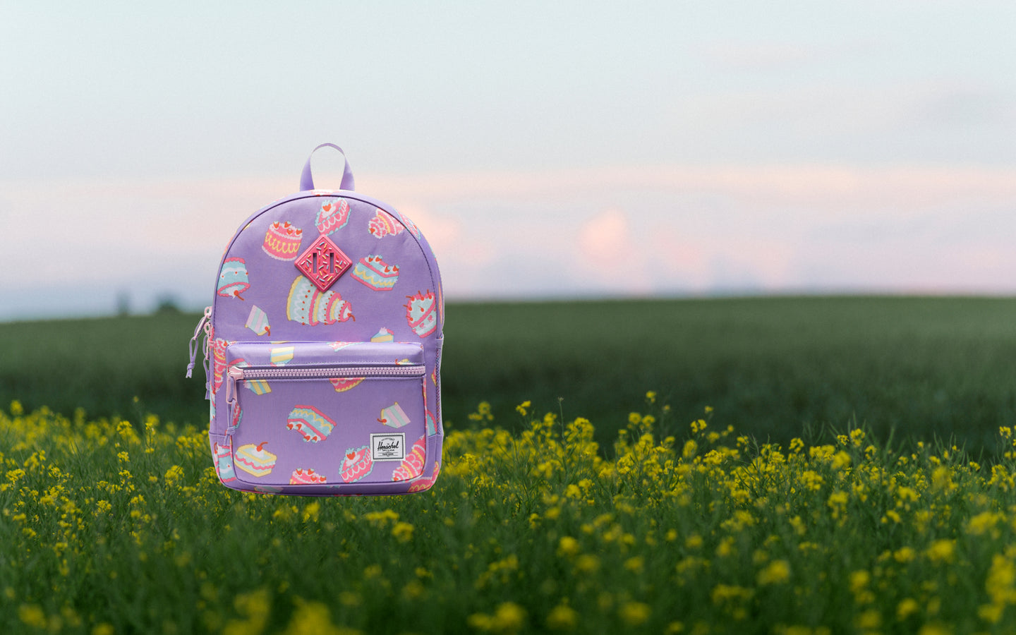 Herschel Heritage Kids Backpack in Cakes colorway, featuring a playful cake print design on a light background.
