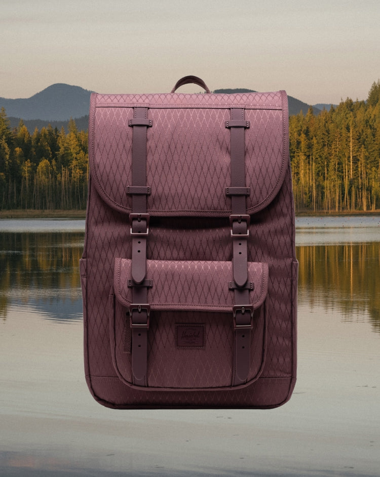 Herschel Little America Mid Backpack in Huckleberry Diamond, a purple patterned backpack with brown rubber straps and a white logo label.