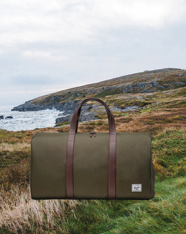 Herschel Novel Duffle bag in Ivy Green color, shown from a side view.