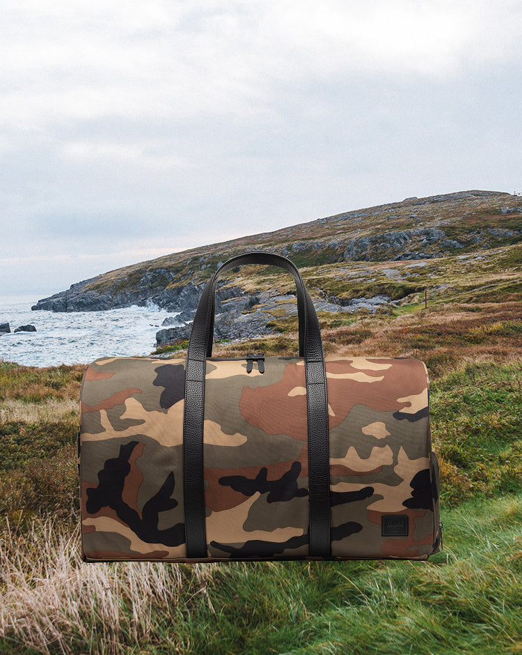 Herschel Novel Duffle bag in Woodland Camo with a Black Label logo patch.
