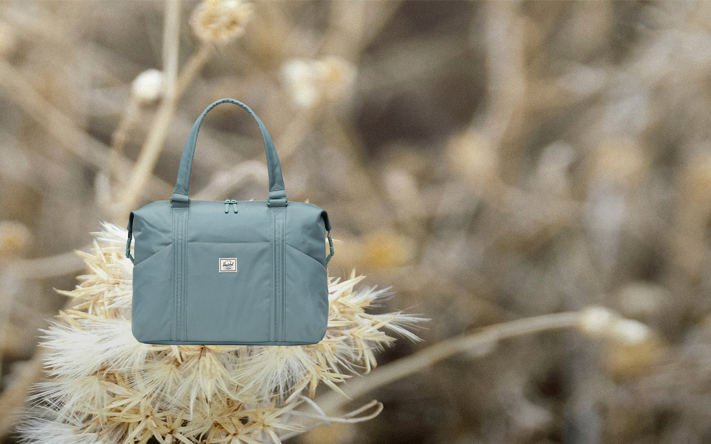 Herschel Supply Co. Strand Duffle Diaper Bag shown from a front angle, featuring top handles and external pockets.