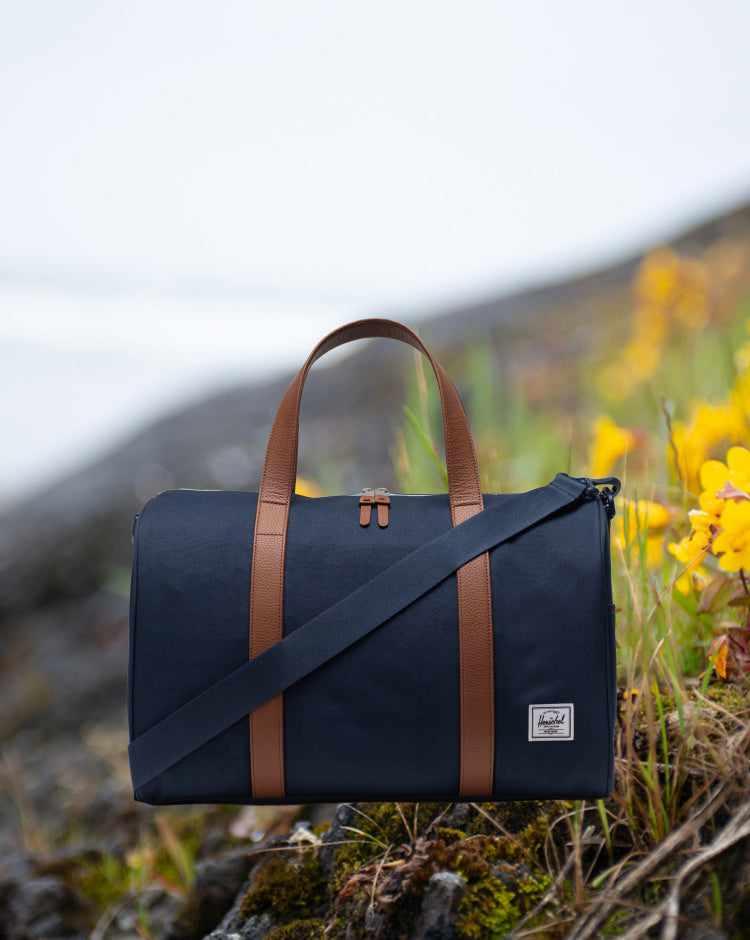 Herschel Supply Co. Novel Carry On Duffle bag in Navy Blue shown from a side view.