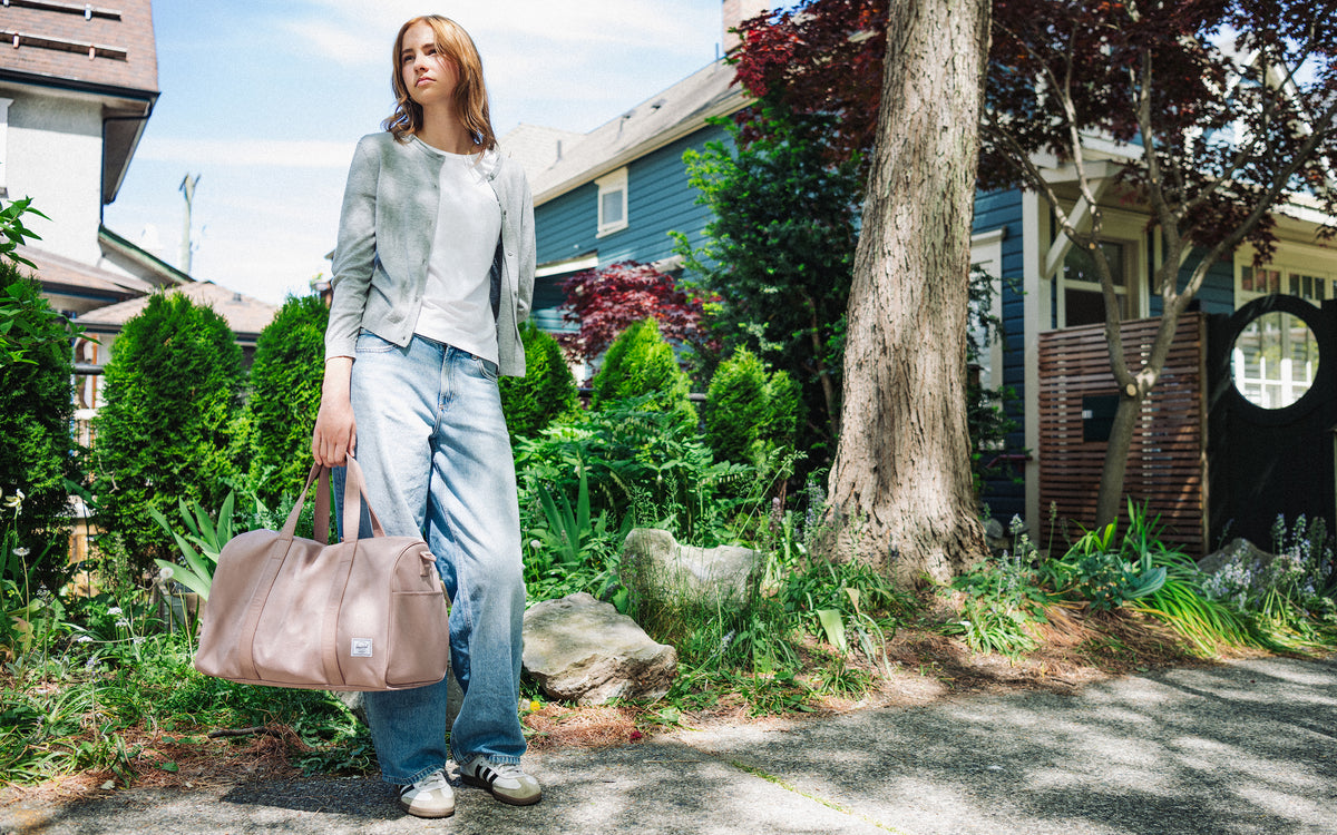 Herschel Novel Carry On Duffle bag in Ash Rose pink, featuring a clean, minimalist design with double top handles and a shoulder strap.
