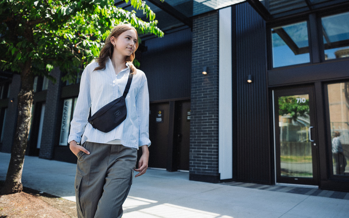 Herschel Classic Hip Pack in Black Tonal, worn as a crossbody bag to show its compact design and adjustable strap.