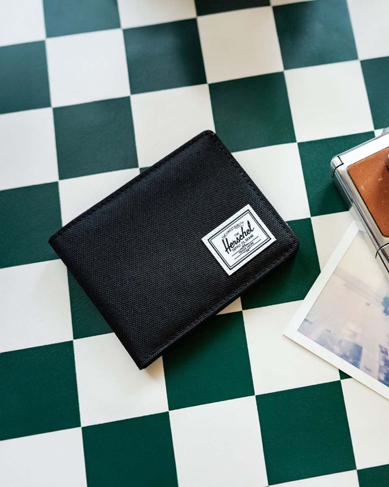 Herschel Supply Co. Roy Wallet in classic black, showing the classic bi-fold design and signature woven label.