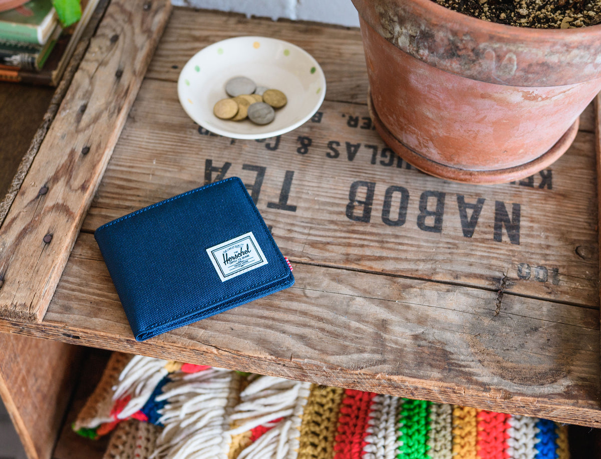 Herschel Supply Co. Roy Wallet in navy blue, showcasing its classic bi-fold design and signature woven label on the front.
