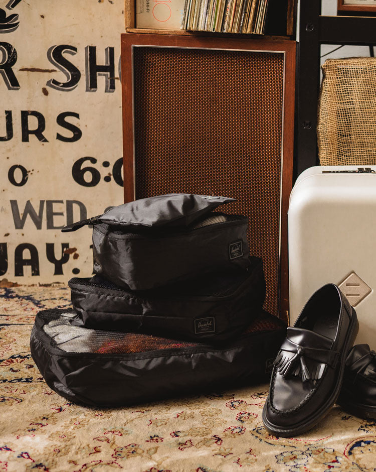 Herschel Supply Co. Black Tonal Kyoto Packing Cubes set of three travel organizers and one pouch laid out against a clean background.