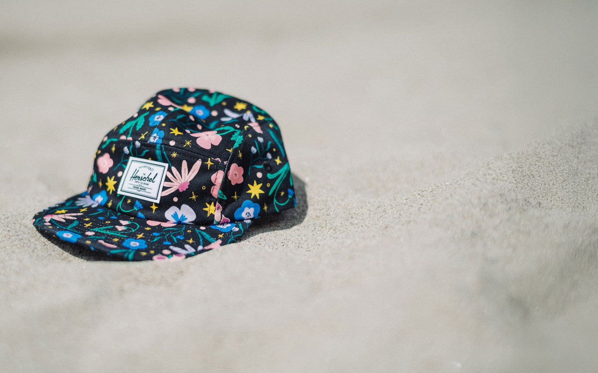 Herschel Supply Co. Glendale Kids Cap in Enchanted Garden floral print, shown on a desktop background.