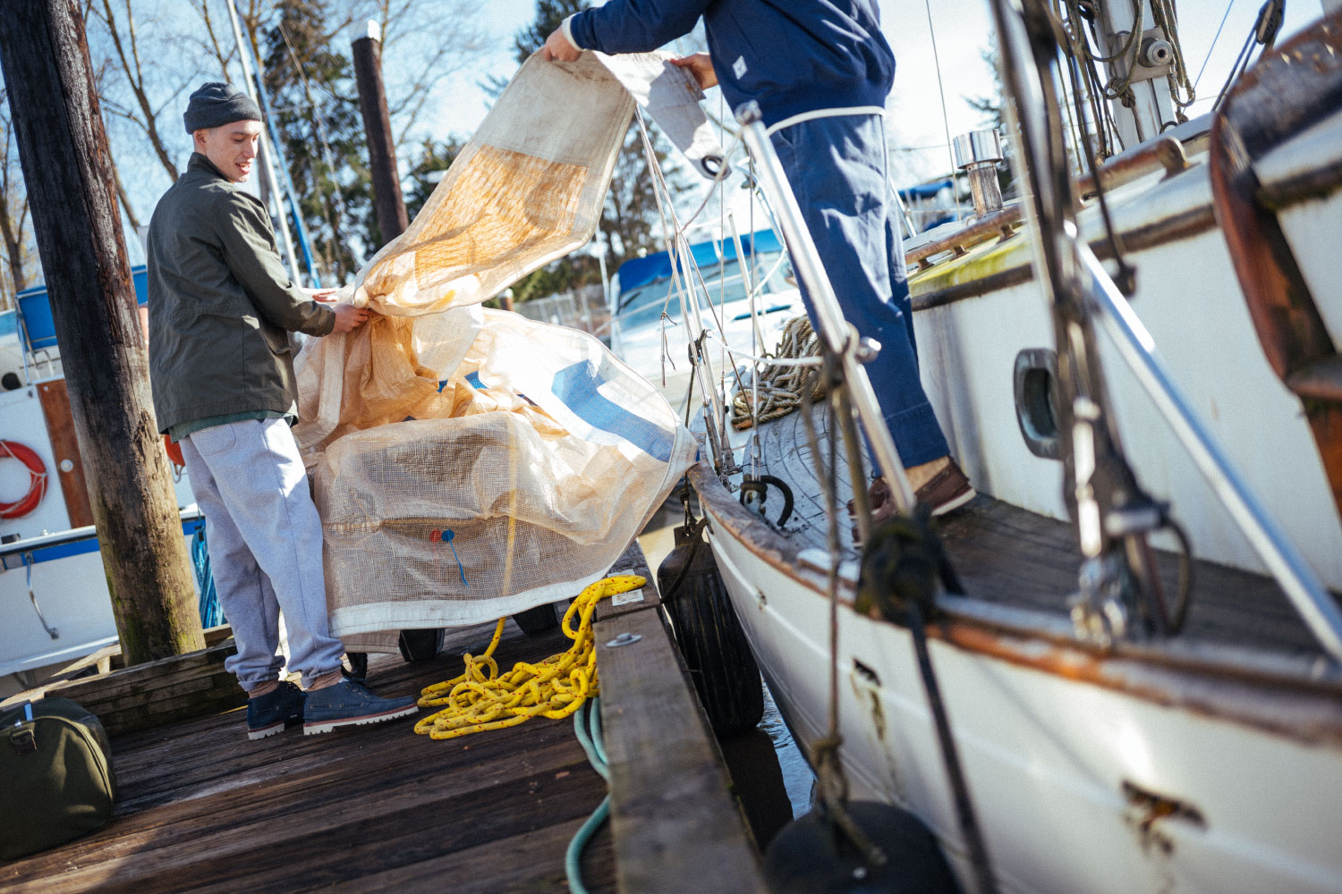 A person taking a tarp off of a sailboat wearing the Herschel Supply Company x Sperry Authentic Original Lug Chukka shoes in Peacoat/Navy/Blanc de Blanc