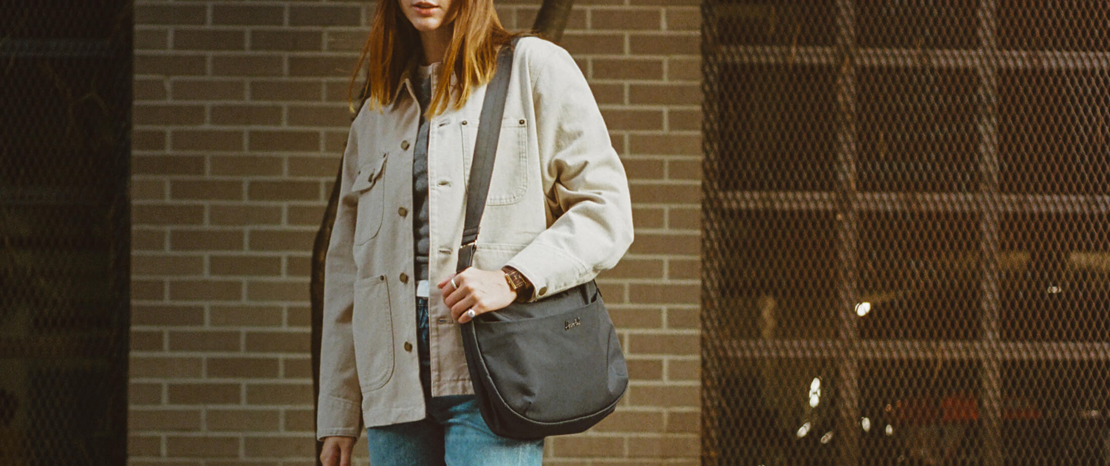 a well dressed woman holds a yara shoulder bag in black over her left shoulder.